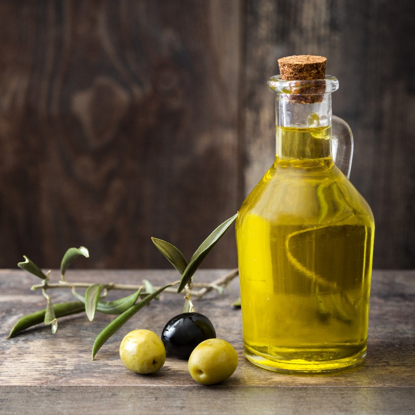 Virgin olive oil in a crystal bottle on wooden background.Copyspace