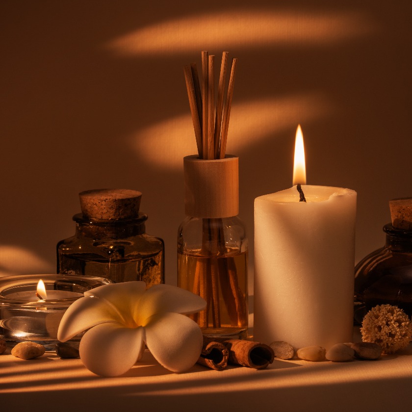 Wunderschönes Spa-Arrangement mit Kerzen, Frangipani-Blüten, Ölfläschchen und weiteren Dekorationselementen.
